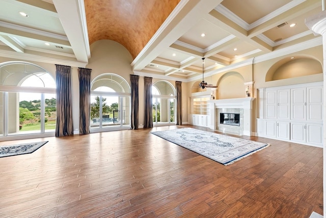 unfurnished living room with wood-type flooring, plenty of natural light, and ornamental molding