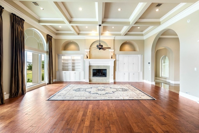 unfurnished living room with crown molding, beam ceiling, coffered ceiling, ceiling fan, and light hardwood / wood-style flooring