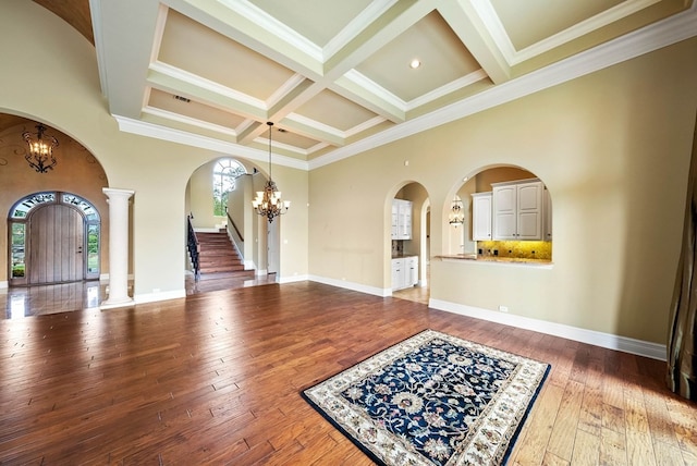 interior space featuring coffered ceiling, wood-type flooring, a notable chandelier, and ornamental molding