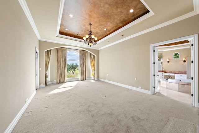 carpeted spare room featuring a chandelier, a tray ceiling, and crown molding