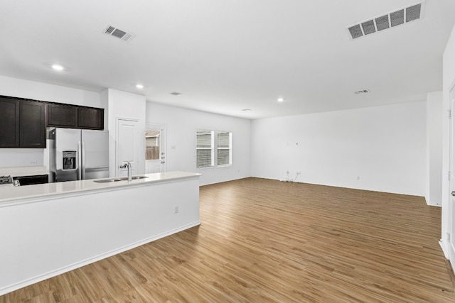 kitchen featuring light wood-type flooring, stainless steel refrigerator with ice dispenser, sink, and dark brown cabinets