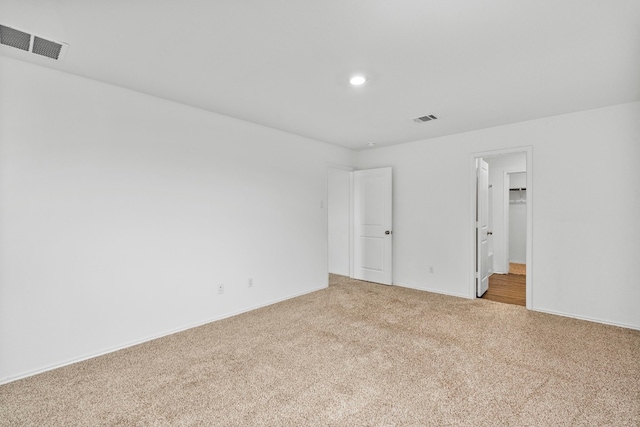 unfurnished bedroom featuring light carpet, a closet, and a walk in closet