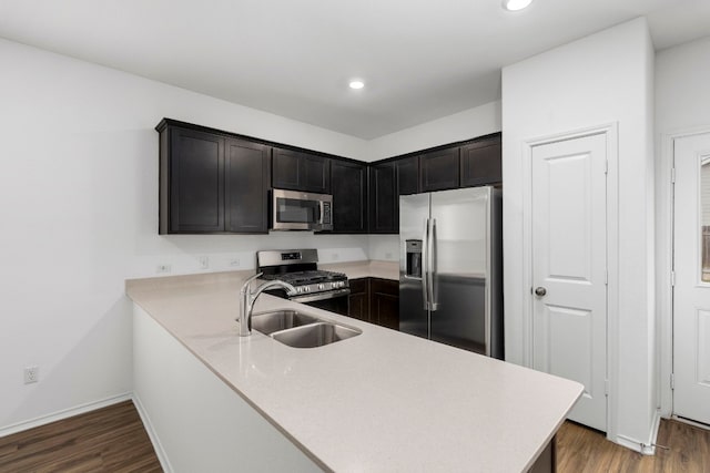 kitchen with stainless steel appliances, sink, dark wood-type flooring, and kitchen peninsula