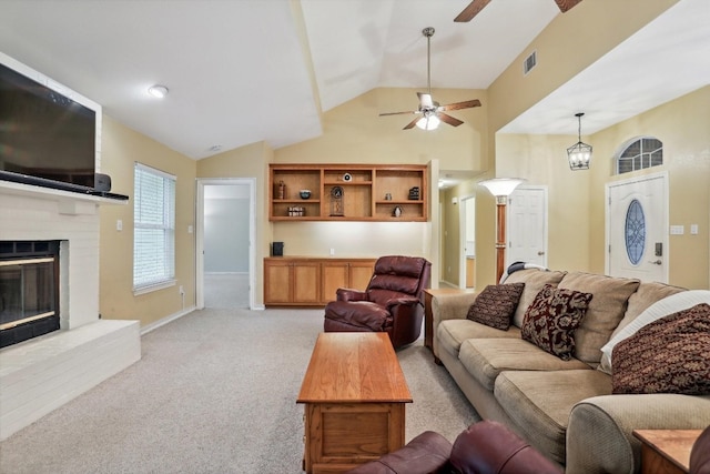 carpeted living room with vaulted ceiling, ceiling fan, and a brick fireplace