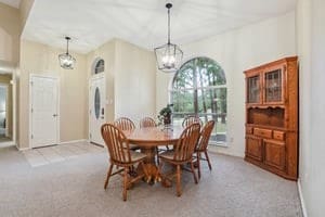 carpeted dining area with an inviting chandelier