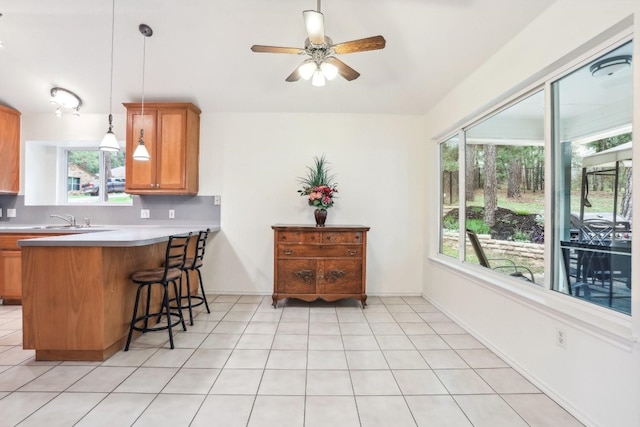 kitchen featuring kitchen peninsula, sink, ceiling fan, light tile patterned flooring, and decorative light fixtures