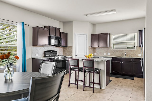 kitchen with dark brown cabinetry, decorative backsplash, and stainless steel gas stove