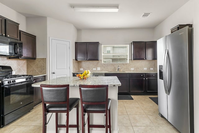 kitchen with dark brown cabinets, black appliances, and a center island