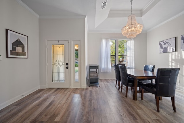 dining room with ornamental molding, wood-type flooring, a chandelier, and a raised ceiling