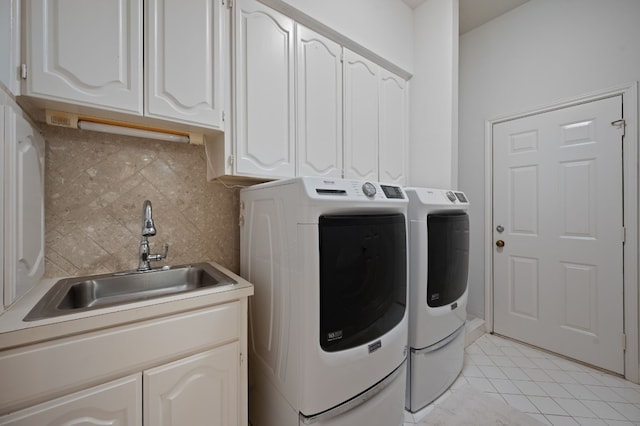 clothes washing area with sink, cabinets, washing machine and clothes dryer, and light tile patterned flooring