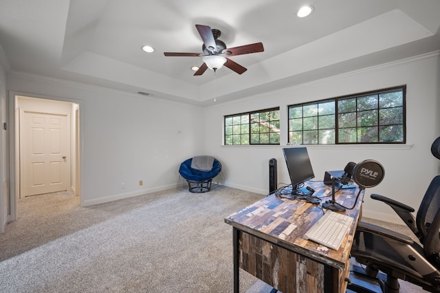 office space featuring ceiling fan, a raised ceiling, crown molding, and light colored carpet