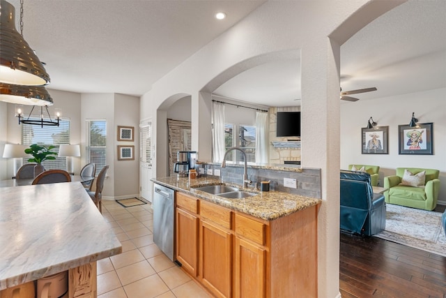 kitchen featuring light stone countertops, backsplash, sink, light hardwood / wood-style flooring, and dishwasher