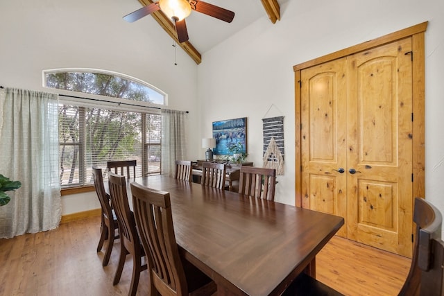 dining room with ceiling fan, beam ceiling, high vaulted ceiling, and light wood-type flooring