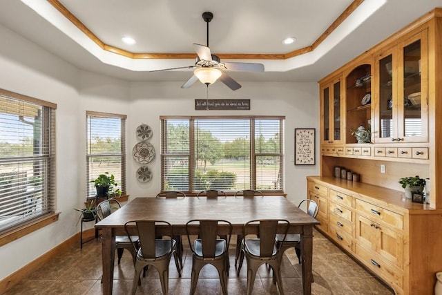 tiled dining room featuring ceiling fan and a raised ceiling