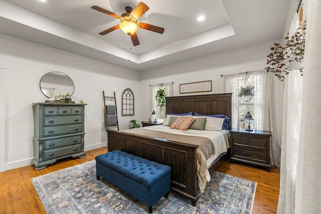 bedroom with a tray ceiling, ceiling fan, and hardwood / wood-style flooring