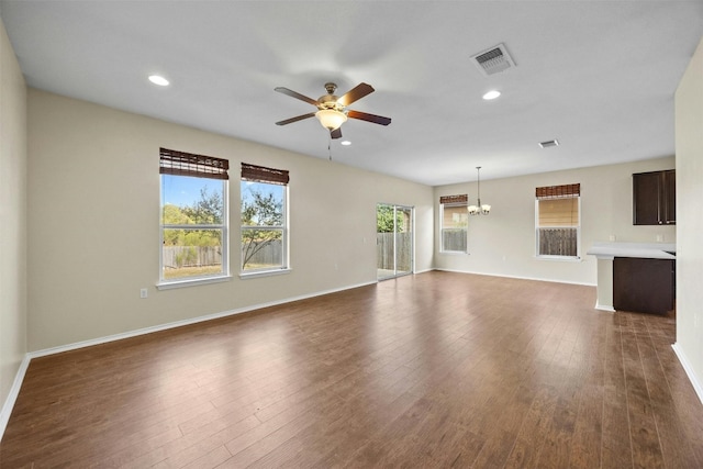 unfurnished living room featuring dark hardwood / wood-style flooring and ceiling fan with notable chandelier