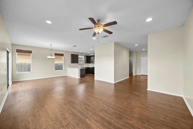 unfurnished living room with sink, ceiling fan with notable chandelier, and dark wood-type flooring