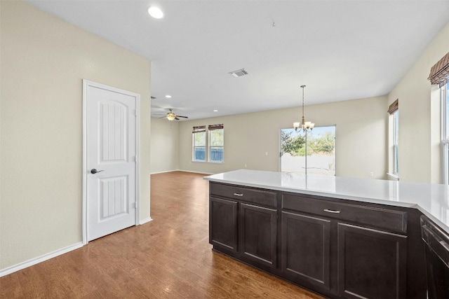 kitchen featuring ceiling fan with notable chandelier, pendant lighting, black dishwasher, dark brown cabinetry, and light wood-type flooring