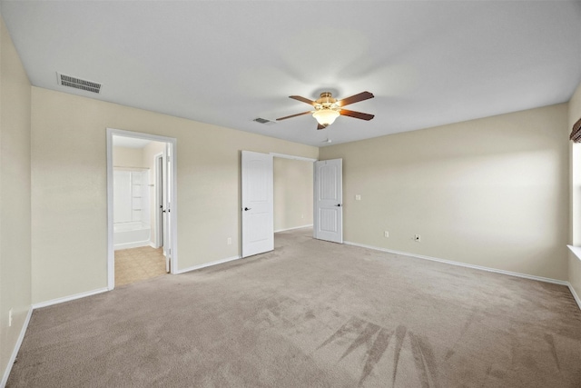 unfurnished bedroom with ceiling fan, ensuite bathroom, and light colored carpet