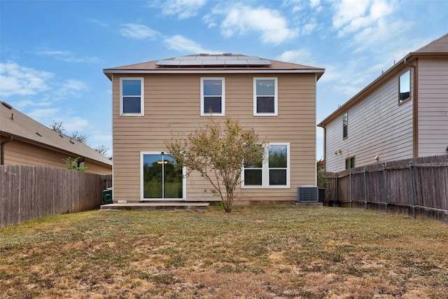 back of property featuring a yard, central AC, and solar panels