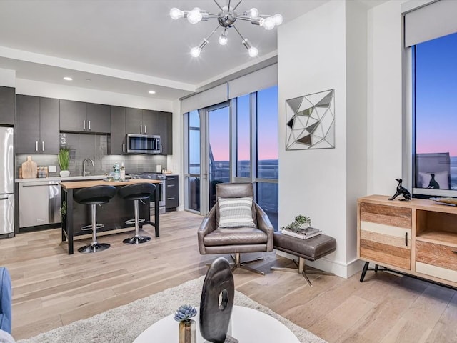 living room featuring sink, light hardwood / wood-style flooring, and a notable chandelier