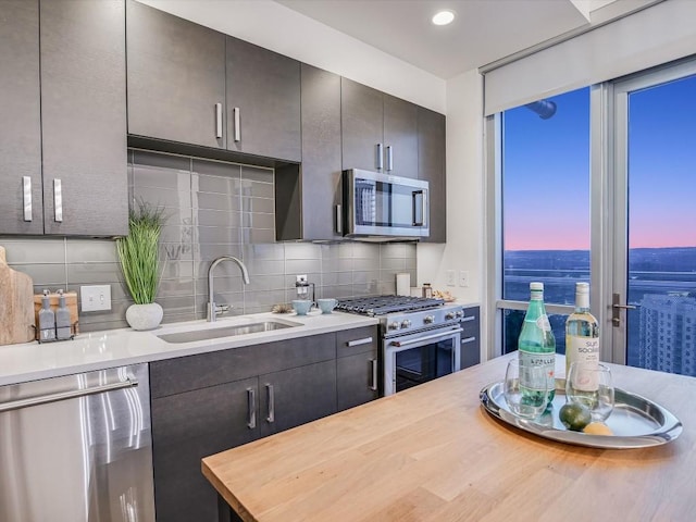 kitchen with butcher block counters, appliances with stainless steel finishes, sink, and backsplash