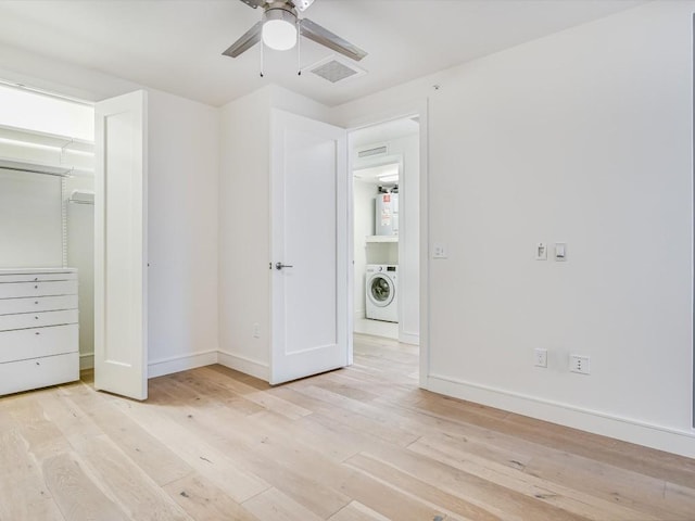 unfurnished bedroom with water heater, a closet, washer / dryer, ceiling fan, and light hardwood / wood-style flooring