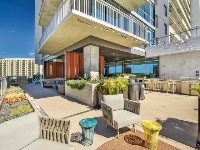 view of patio with outdoor lounge area, a balcony, a grill, and outdoor dry bar