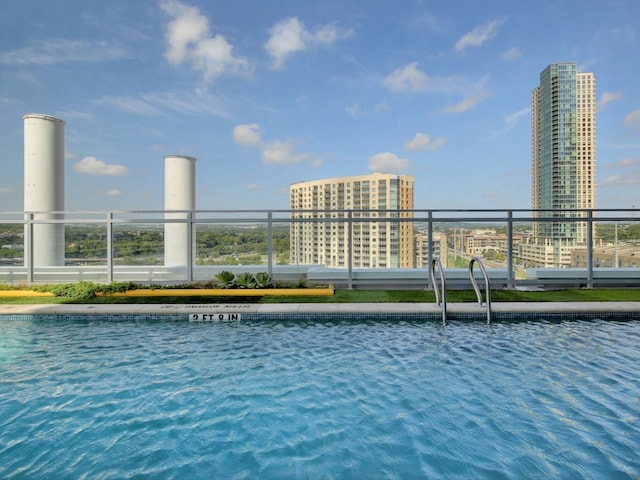 view of pool with a view of city and a water view