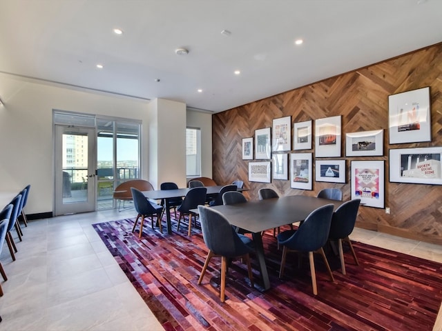 dining room with recessed lighting, french doors, an accent wall, and wood walls