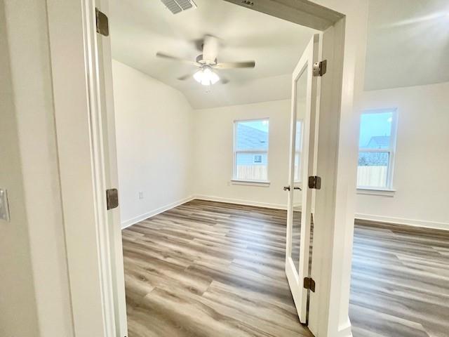 unfurnished room featuring hardwood / wood-style flooring, lofted ceiling, and ceiling fan