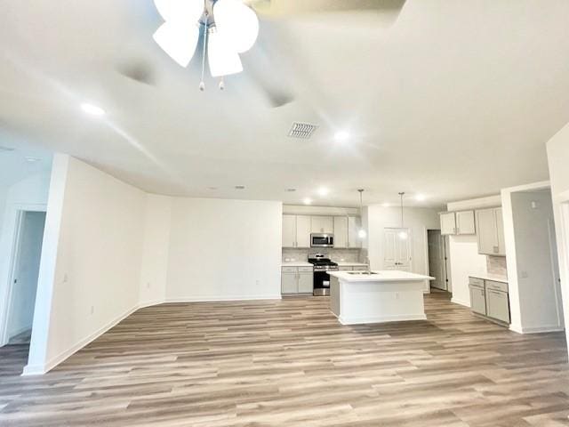 unfurnished living room featuring ceiling fan, sink, and light wood-type flooring