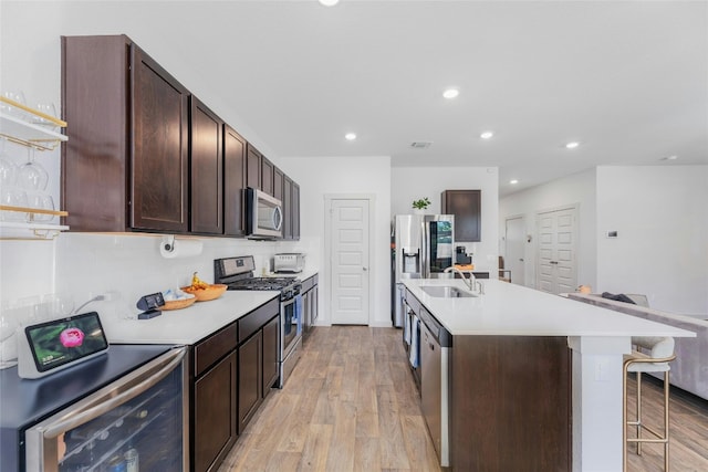 kitchen featuring stainless steel appliances, a breakfast bar area, sink, a kitchen island with sink, and light wood-type flooring