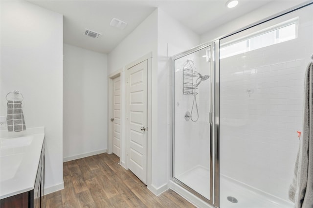 bathroom with hardwood / wood-style flooring, a shower with shower door, and vanity