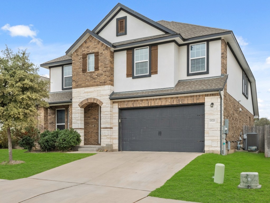 view of front of home with a garage, a front yard, and central AC