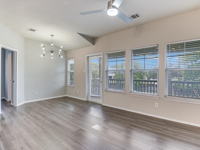 empty room with hardwood / wood-style floors and ceiling fan with notable chandelier