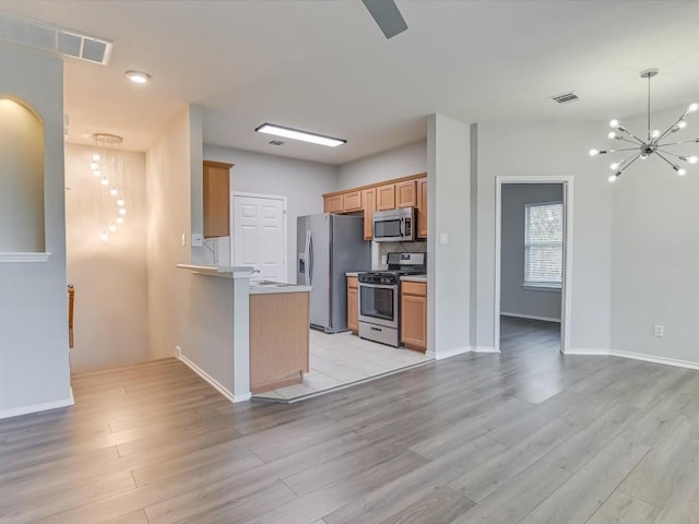 kitchen featuring a peninsula, stainless steel appliances, visible vents, a chandelier, and light wood-style flooring