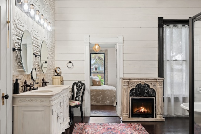 bathroom featuring a tub, wood-type flooring, wooden walls, and a high end fireplace