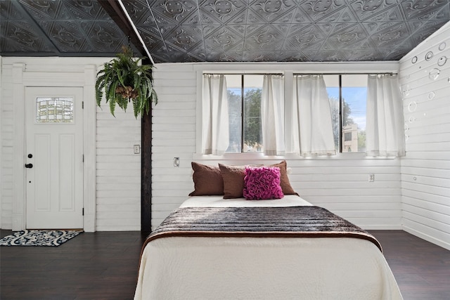 bedroom featuring dark hardwood / wood-style flooring, wood walls, and lofted ceiling