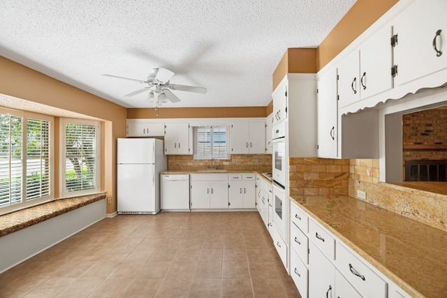 kitchen with light tile patterned flooring, white cabinetry, ceiling fan, white appliances, and decorative backsplash