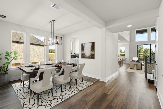 dining space with dark wood-type flooring, a wealth of natural light, and a notable chandelier