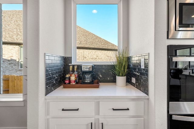 interior space with appliances with stainless steel finishes, white cabinetry, and decorative backsplash