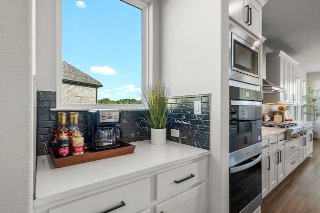 kitchen featuring dark wood-type flooring, tasteful backsplash, appliances with stainless steel finishes, and white cabinets