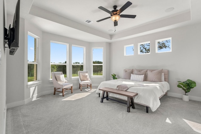 carpeted bedroom featuring a tray ceiling and ceiling fan