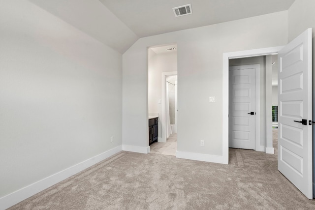 unfurnished bedroom with connected bathroom, lofted ceiling, and light colored carpet