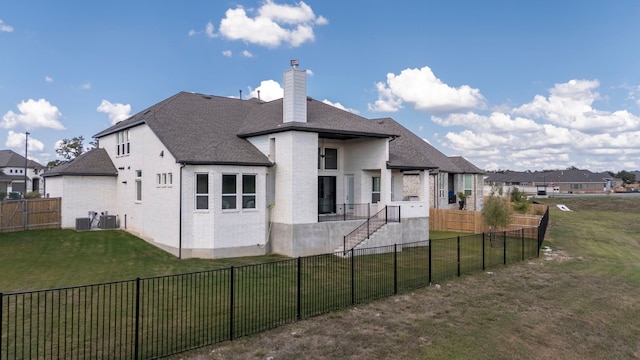 rear view of property with central AC unit and a lawn