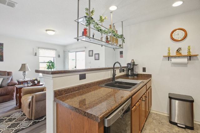 kitchen featuring dark stone counters, light wood-type flooring, sink, dishwasher, and kitchen peninsula