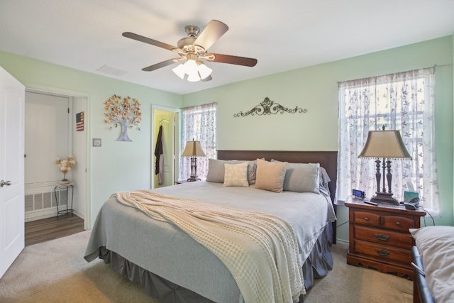 bedroom featuring multiple windows, light colored carpet, and ceiling fan