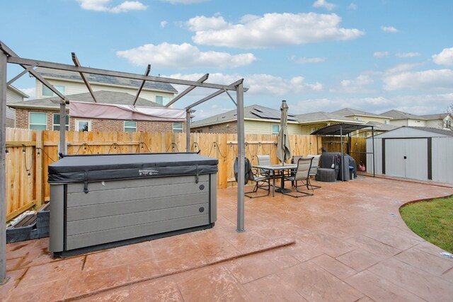 view of patio / terrace featuring a hot tub and a storage shed