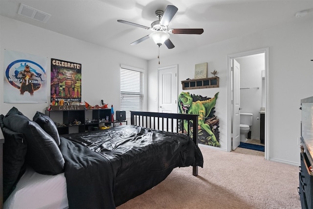 bedroom with ceiling fan, light carpet, and connected bathroom